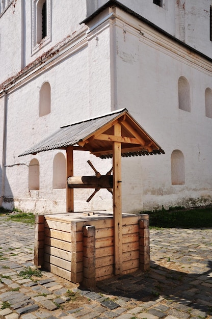 Pozzo di legno. Fortino di un pozzo fatto di sbarre, nel cortile del monastero. Pozzi sullo sfondo del muro del monastero.