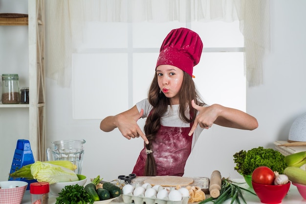 Pranzare. bambino che indossa l'uniforme da cuoco. usa solo prodotti sani. ricco di vitamine. stare a dieta. giovane fornaio che prepara il pasto in cucina. cucinare il cibo per la cena. felice sviluppo dell'infanzia.