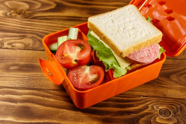 Pranzo a scuola con panino e verdure fresche sul tavolo di legno