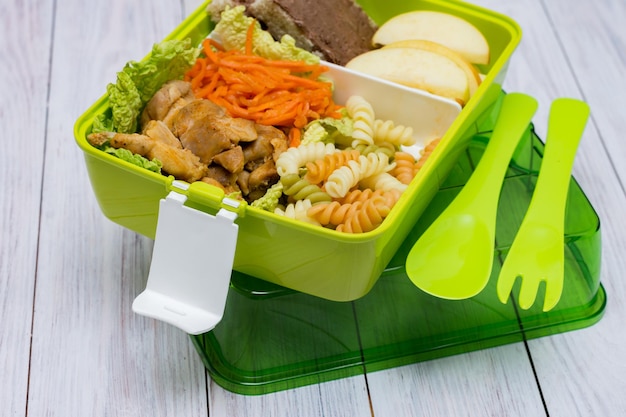 Pranzo al sacco verde con posate Pasta con carote di pollo Tagliare la mela e toast con pasta di cioccolato Alimentazione sana Copiare lo spazio