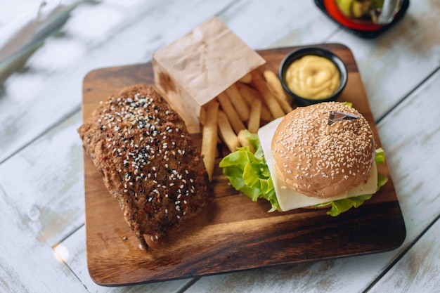 Pranzo appetitoso fast food su un supporto in legno con patatine fritte e salsa.