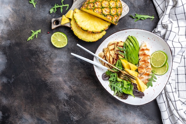 Pranzo in insalatiera assortita con pollo alla griglia, halloumi, avocado, rucola verde, lime