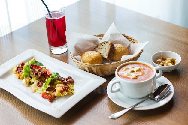 Pranzo in tavola: zuppa di purea di pomodoro, insalata di verdure fresche e pane e pomodori secchi