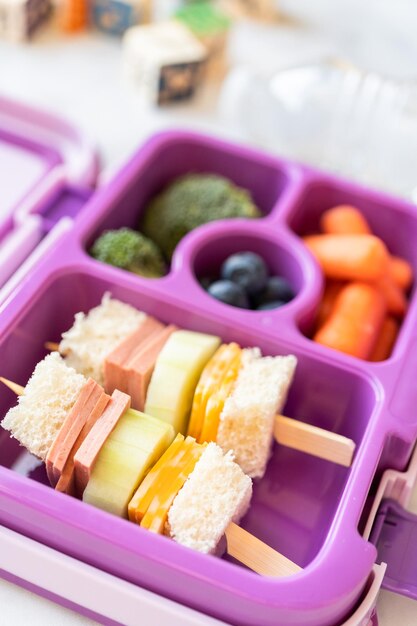 Pranzo scolastico sano con panino kebab e verdure in bento box.