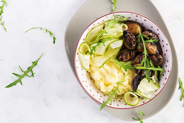 Pranzo vegano sano con purè di patate e funghi arrostiti con cetriolo fresco