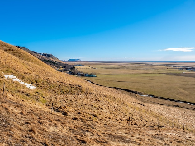 Prato e campo delle colline delle montagne vicino alla cascata di Skogafoss nella stagione invernale in Islanda