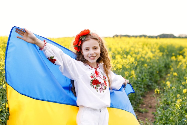 Prega per l'Ucraina Bambino con bandiera ucraina nel campo di colza Ragazza con bandiera nazionale che prega per la pace Bambino felice che celebra il Giorno dell'Indipendenza