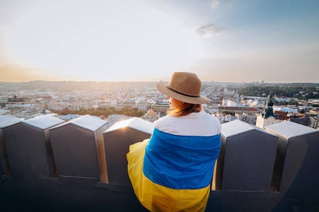 Prega per la donna UkrainexAA sta con la bandiera nazionale ucraina e la sventola pregando per la pace al tramonto a LvivxAA simbolo dell'indipendenza e della forza del popolo ucraino