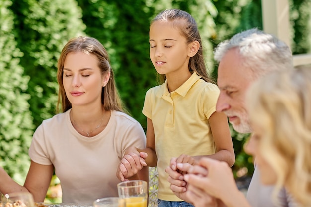 pregare. Una famiglia che si tiene per mano e prega insieme prima di cena