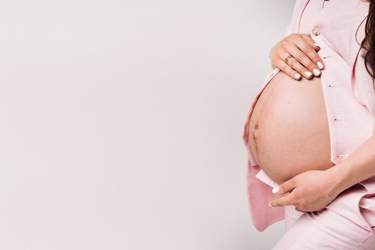 Pregnant woman in a suit close-up on a gray background.