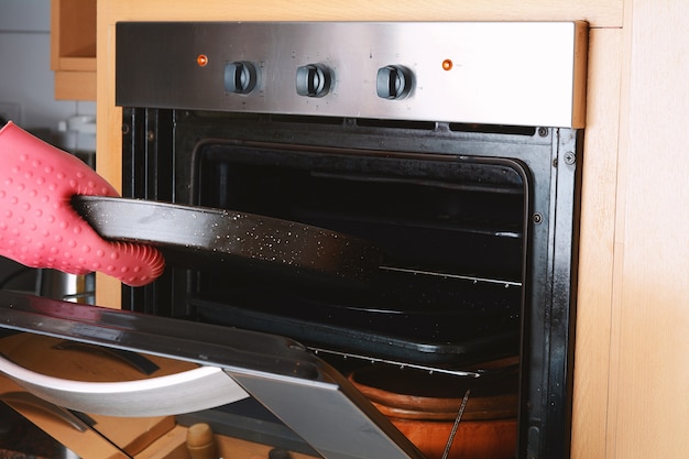 Prelevare il vassoio da forno fuori dal forno con i guanti da cucina