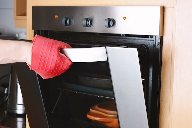 Prelevare il vassoio da forno fuori dal forno con i guanti da cucina