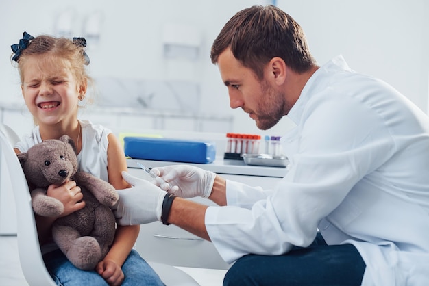 Prelievo di sangue. La bambina con il suo orsacchiotto è in clinica con il dottore.