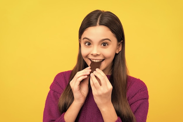 Premiati con un boccone Ragazza felice mangia cioccolato Mangiare cioccolato Godendo di uno spuntino dolce