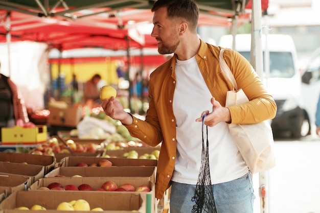 Prende una mela Un uomo bello è al mercato di strada o al bazar