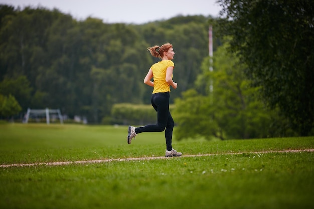 Prendendo in una corsa nel parco Inquadratura di una donna che corre lungo un sentiero in un parco