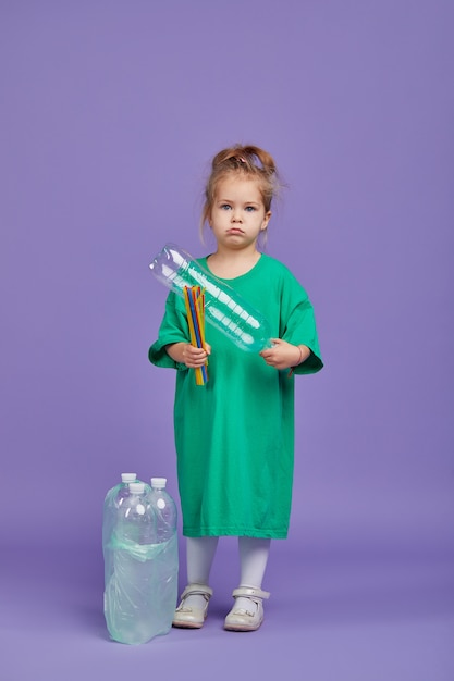 Prendersi cura dell'ambiente. La bambina è un cestino di plastica separato da riciclare. Spazio di studio dai colori vivaci