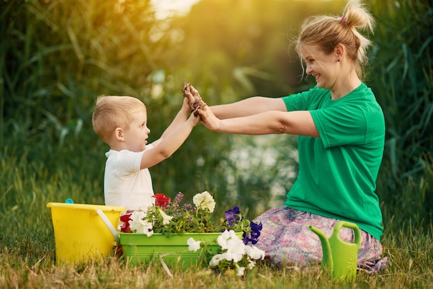 Prendersi cura della natura. Madre e figlio che piantano piantina in terra su assegnazione sulla sponda del fiume. Concetto di botanica ed ecologia.