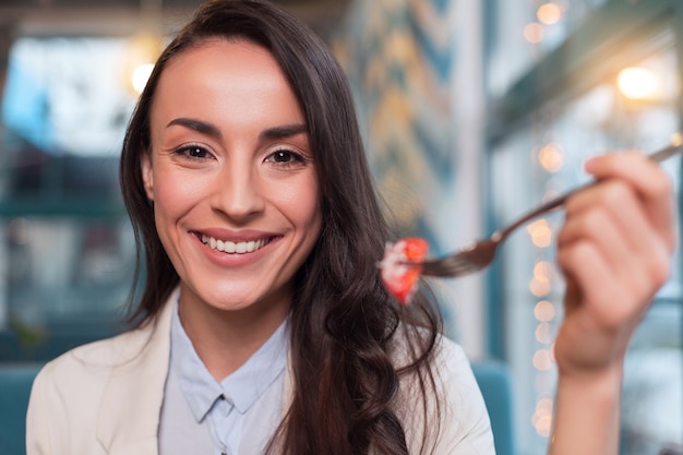 Prenditi cura di me. Forcella in aumento donna piuttosto bella vigorosa mentre guarda la fotocamera e consuma pomodoro