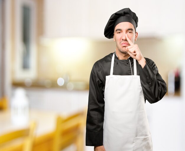 Preoccupato giovane chef facendo un cattivo odore di gesto