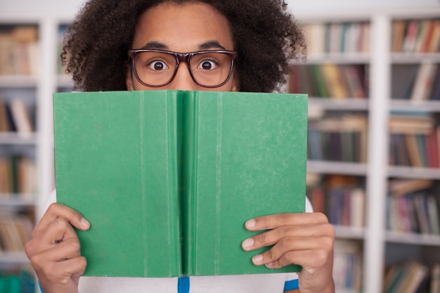 Preoccupato per i suoi esami. Adolescente africano terrorizzato che guarda fuori dal libro