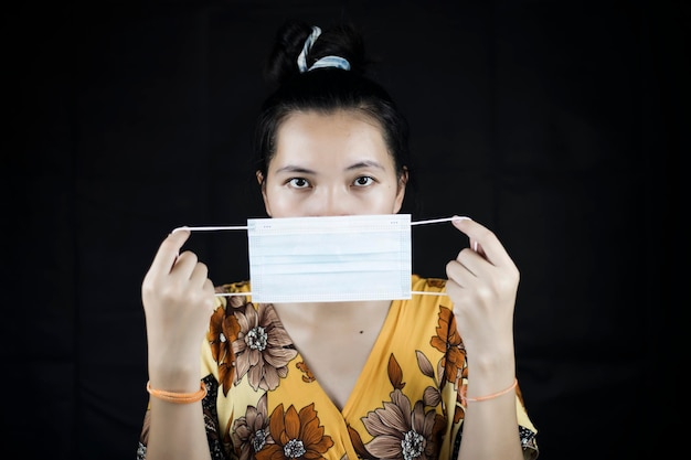 Preoccupato spavento donna asiatica in preda al panico in maschera medica su sfondo nero preoccupata per il virus corona