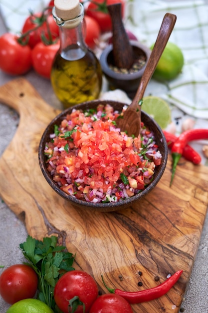 Preparare la salsa, in una ciotola di legno, immergere i pomodori e la cipolla tritati all'aglio