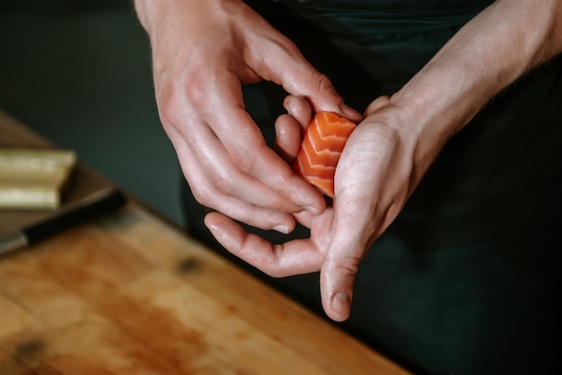 Preparare sushi e involtini a casa. Primo piano della mano di un uomo