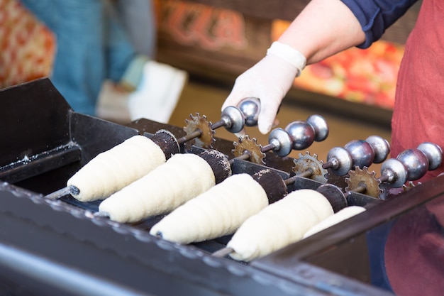 Preparare Trdelnik. La tradizionale pasticceria dolce ceca venduta nelle strade di Praga e in altre città della Repubblica Ceca.