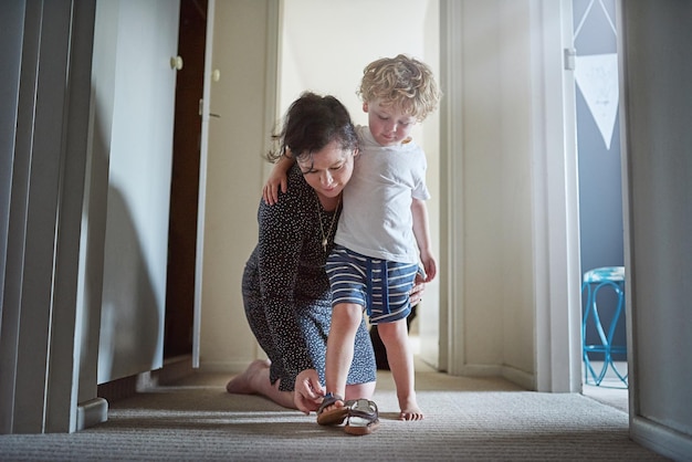 Prepararsi per il divertimento che ci aspetta Inquadratura di una madre che aiuta il figlio a mettersi le scarpe a casa