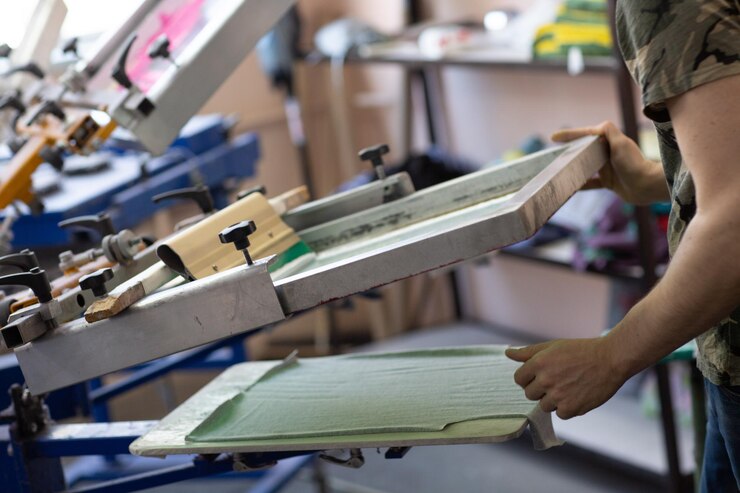 Prepararsi per la stampa e applicare il processo di stampa serigrafica serigrafica su tessuto presso la fabbrica di vestiti clothes
