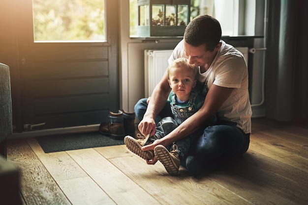 Prepararsi per una giornata Ripresa di un padre che aiuta il figlio a mettersi le scarpe a casa