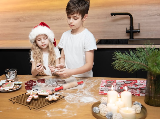 Preparativi per le vacanze di Natale. Bambini: un ragazzo e una ragazza stanno preparando il pan di zenzero in cucina