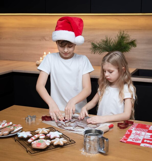 Preparativi per le vacanze di Natale. Bambini: un ragazzo e una ragazza stanno preparando il pan di zenzero in cucina