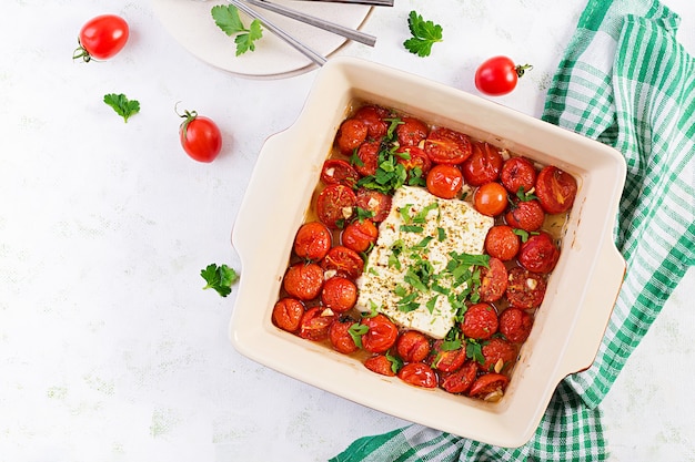 Preparazione degli ingredienti per fetapasta. Ricetta di pasta al forno feta di tendenza a base di pomodorini, formaggio feta, aglio ed erbe aromatiche. Vista dall'alto, sopra, copia dello spazio.