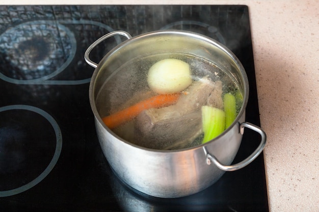 Preparazione del brodo di carne in pentola su un fornello in ceramica