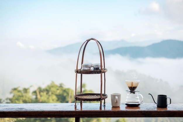 Preparazione del caffè Arabica da parte dell'attrezzatura per il gocciolamento del caffè vintage impostata su un tavolo di legno al mattino con sfondo di montagna e natura