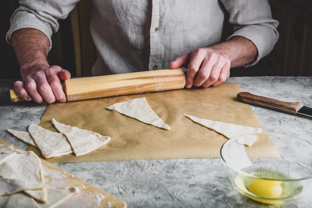 Preparazione del croissant fatto in casa. Baker arrotola la pasta sfoglia