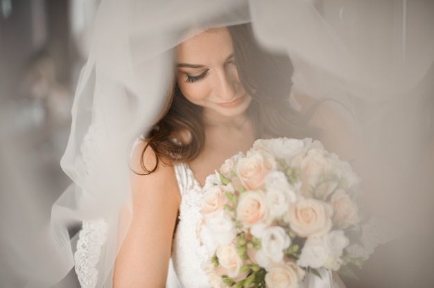 Preparazione del mattino sposa. Sposa adorabile in un velo bianco con un mazzo di nozze