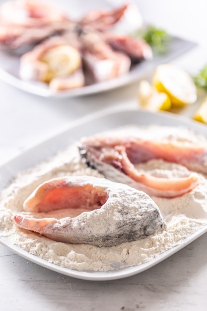 Preparazione del pesce fresco prima della frittura avvolgendolo nella farina.