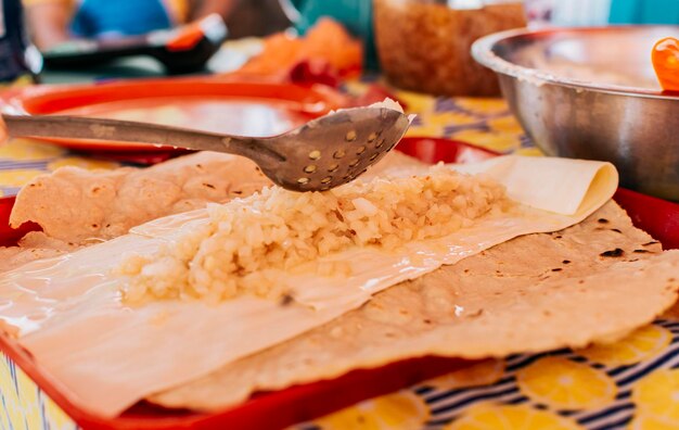 Preparazione del tradizionale quesillo nicaraguense Mani che preparano un delizioso quesillo nicaraguense Cibo centroamericano il quesillo Veduta del tradizionale quesillo con cipolla sottaceto