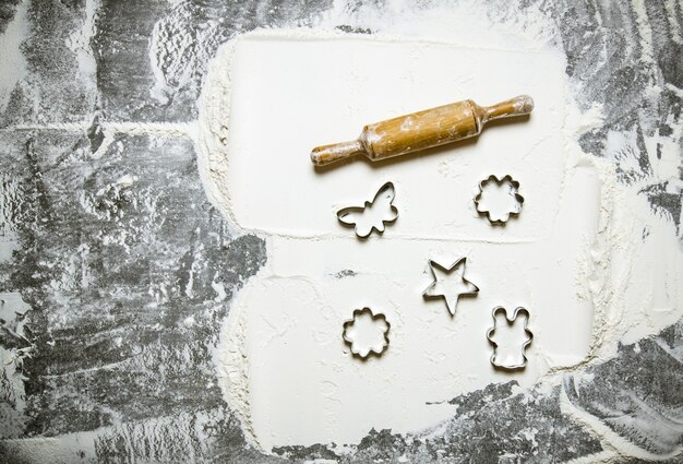 Preparazione dell'impasto. Farina con il mattarello e formare per i biscotti. Sul tavolo di pietra. Spazio libero per il testo. Vista dall'alto