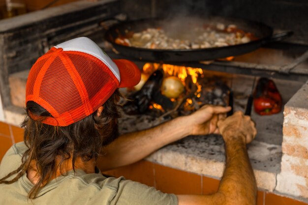 Preparazione della brace della paella valenciana con brace e verdure