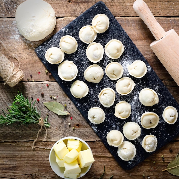 Preparazione della cottura di ravioli pelmeni fatti in casa o gnocchi con carne su tavolo in legno vista dall'alto Vista dall'alto Stile rustico