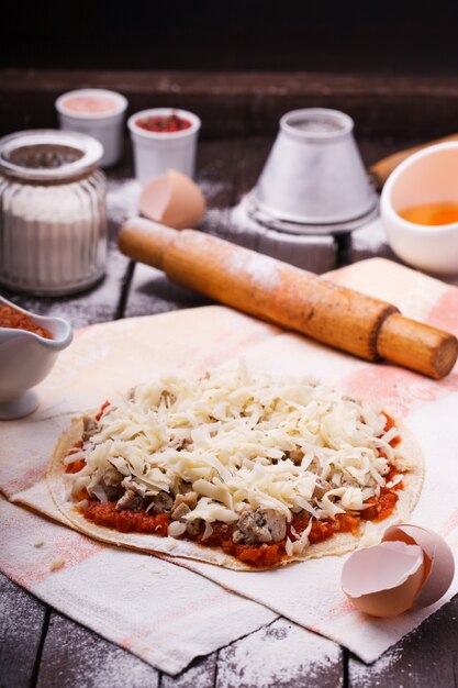 Preparazione della pizza circondata da ingredienti