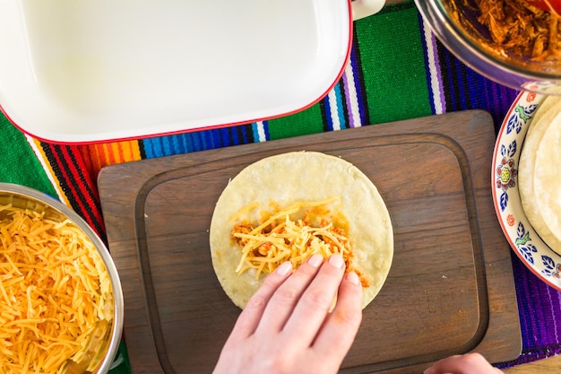 Preparazione delle enchiladas di pollo con formaggio cheddar e salsa.