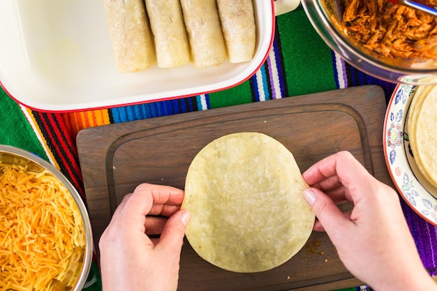 Preparazione delle enchiladas di pollo con formaggio cheddar e salsa.