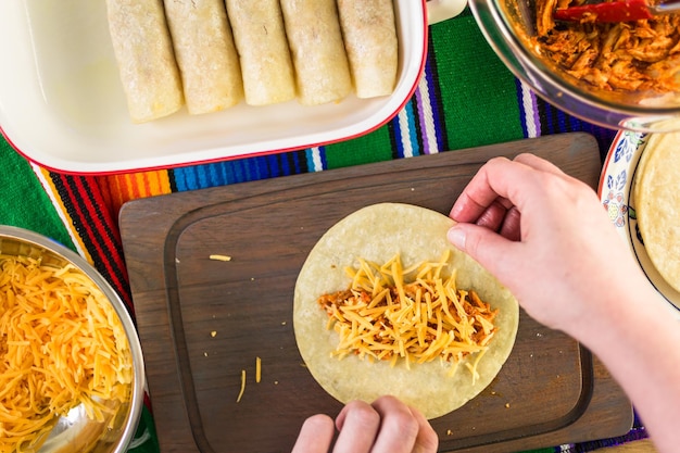 Preparazione delle enchiladas di pollo con formaggio cheddar e salsa.