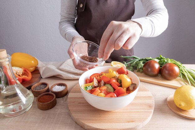 Preparazione di cibi deliziosi e sani le mani di una giovane ragazza cospargono un'insalata di verdure tritate con dieta di semi di lino