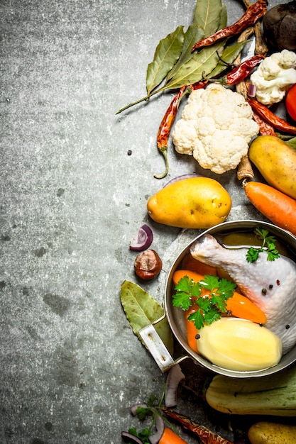 Preparazione di fragrante zuppa di pollo con verdure fresche. Sul tavolo di pietra.